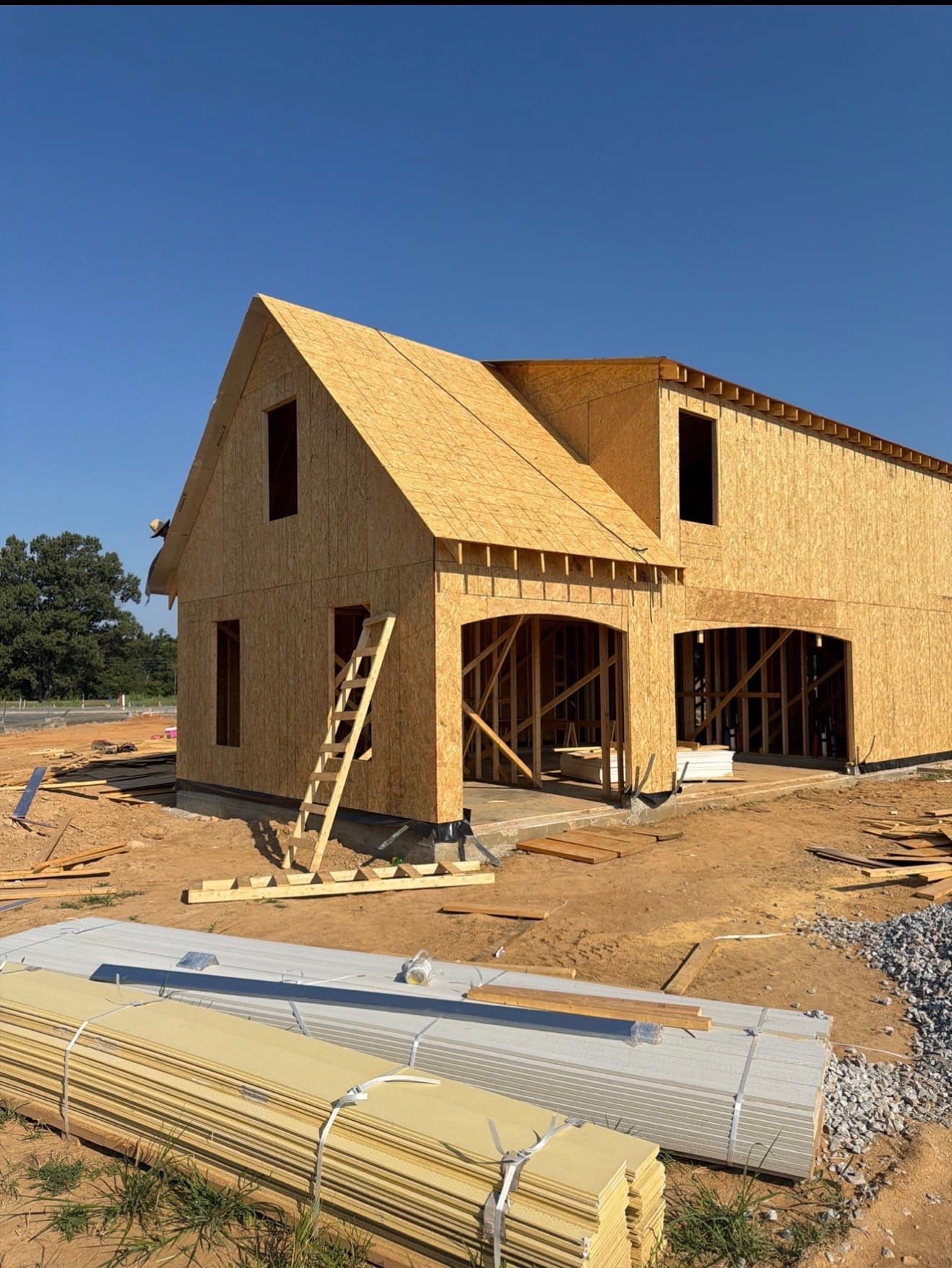 Sheathed gable end of a Memphis-area home with siding material stacked on site