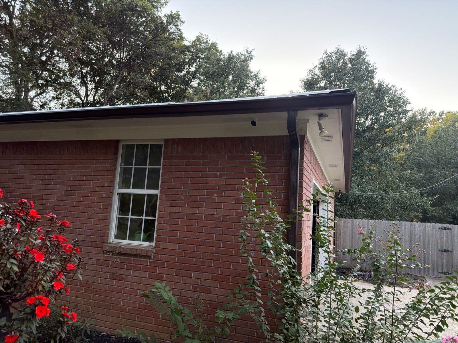 New Royal Brown gutter and downspout on the corner of a brick home beside a window