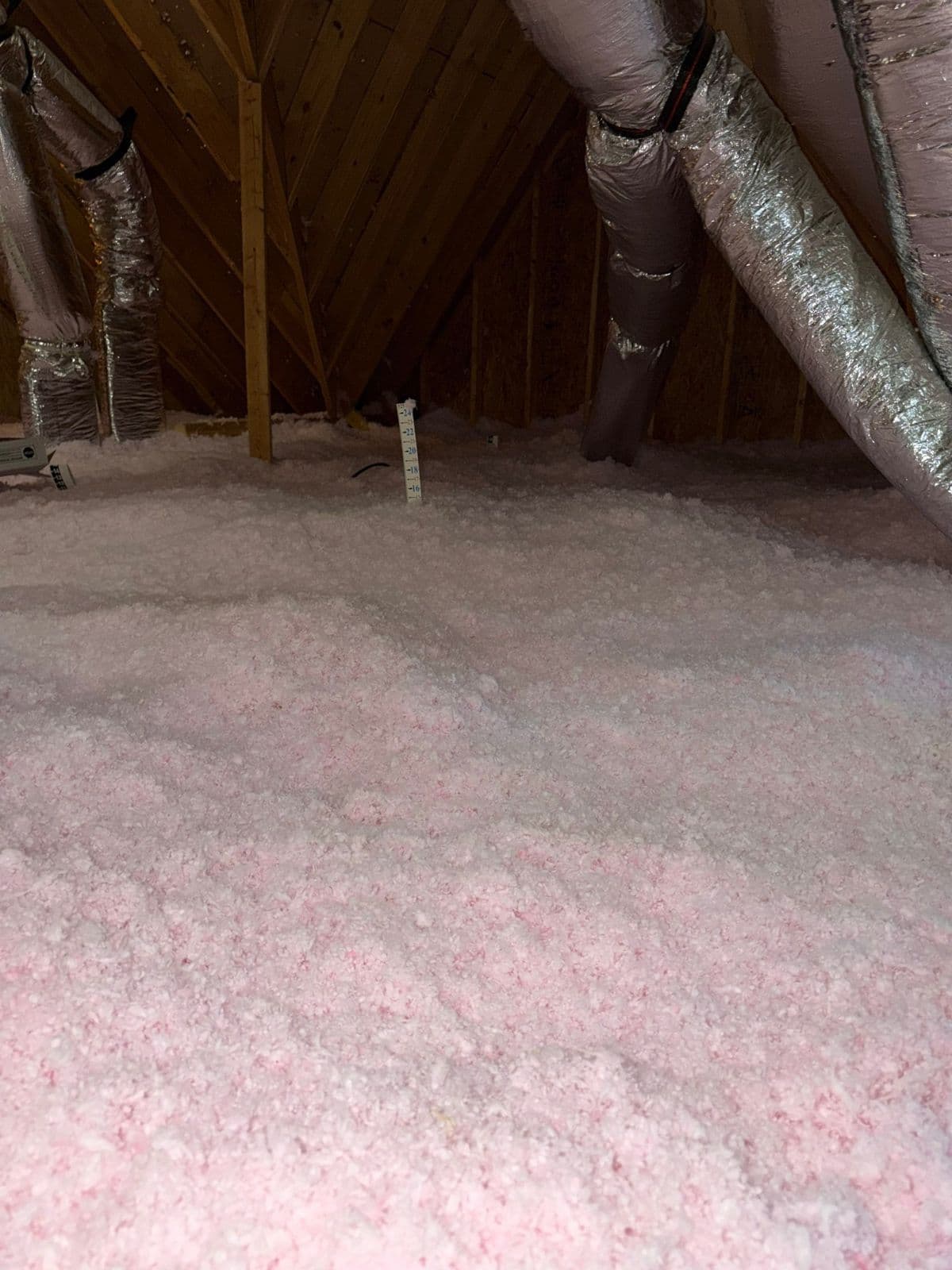 Attic floor covered in an even, deep layer of new pink fiberglass insulation