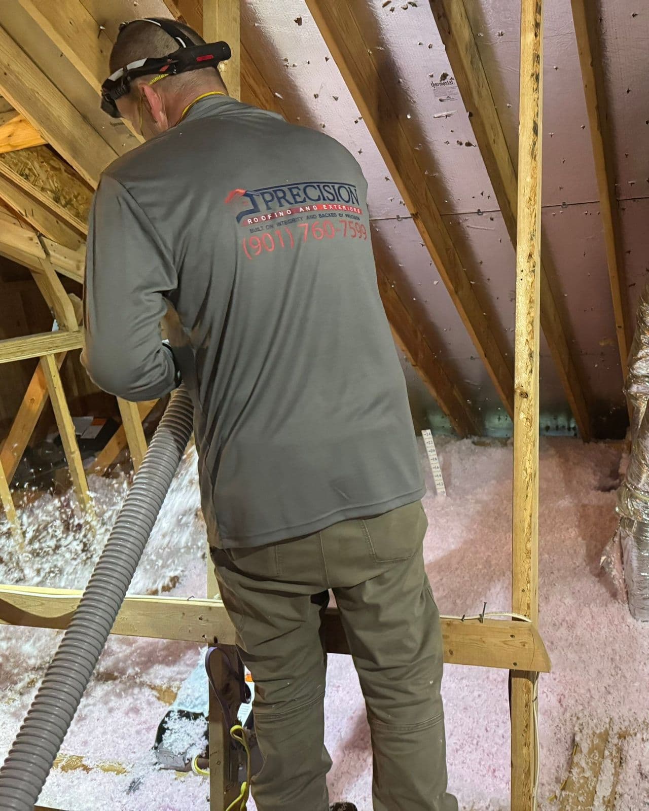 Precision Roofing crew member blowing fiberglass insulation into an attic