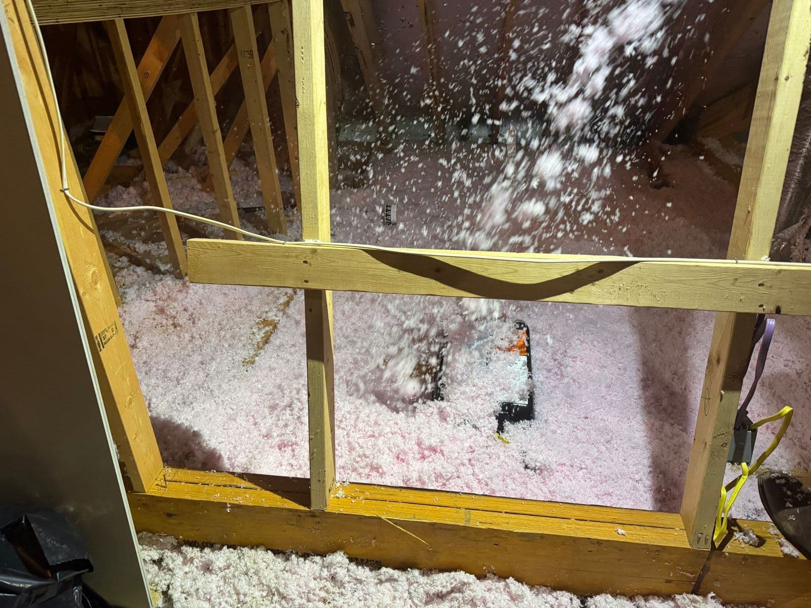 Loose-fill fiberglass insulation being blown into an attic bay