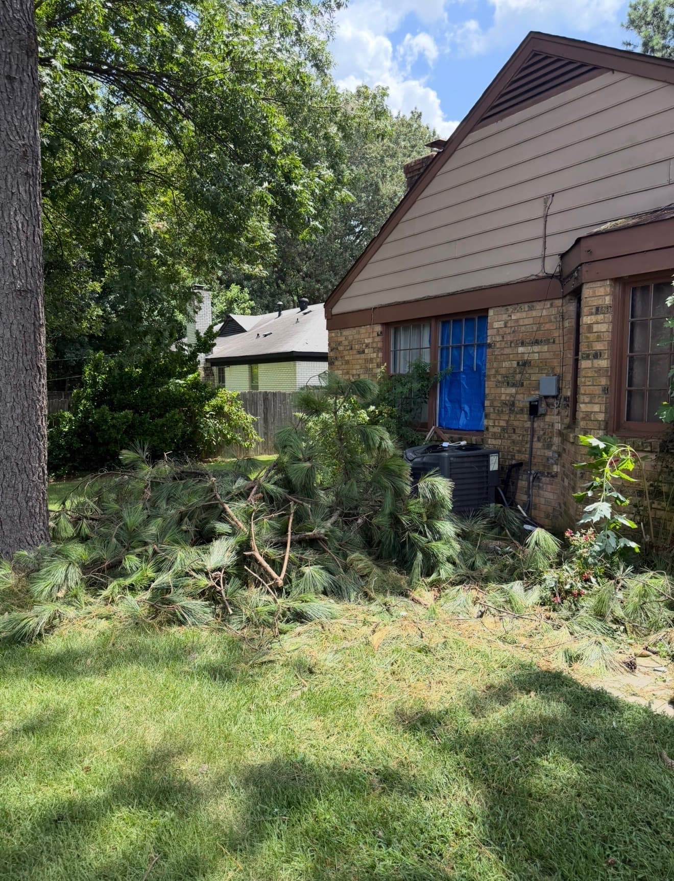 Storm debris down beside a Memphis-area home with the damaged opening tarped over