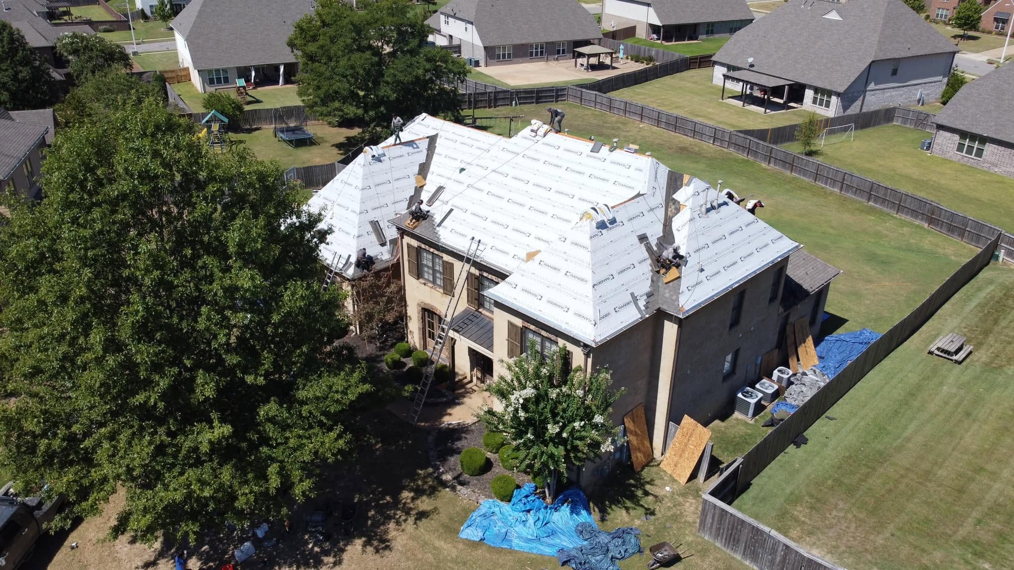 Aerial view of a full roof replacement in progress on a large Mid-South home