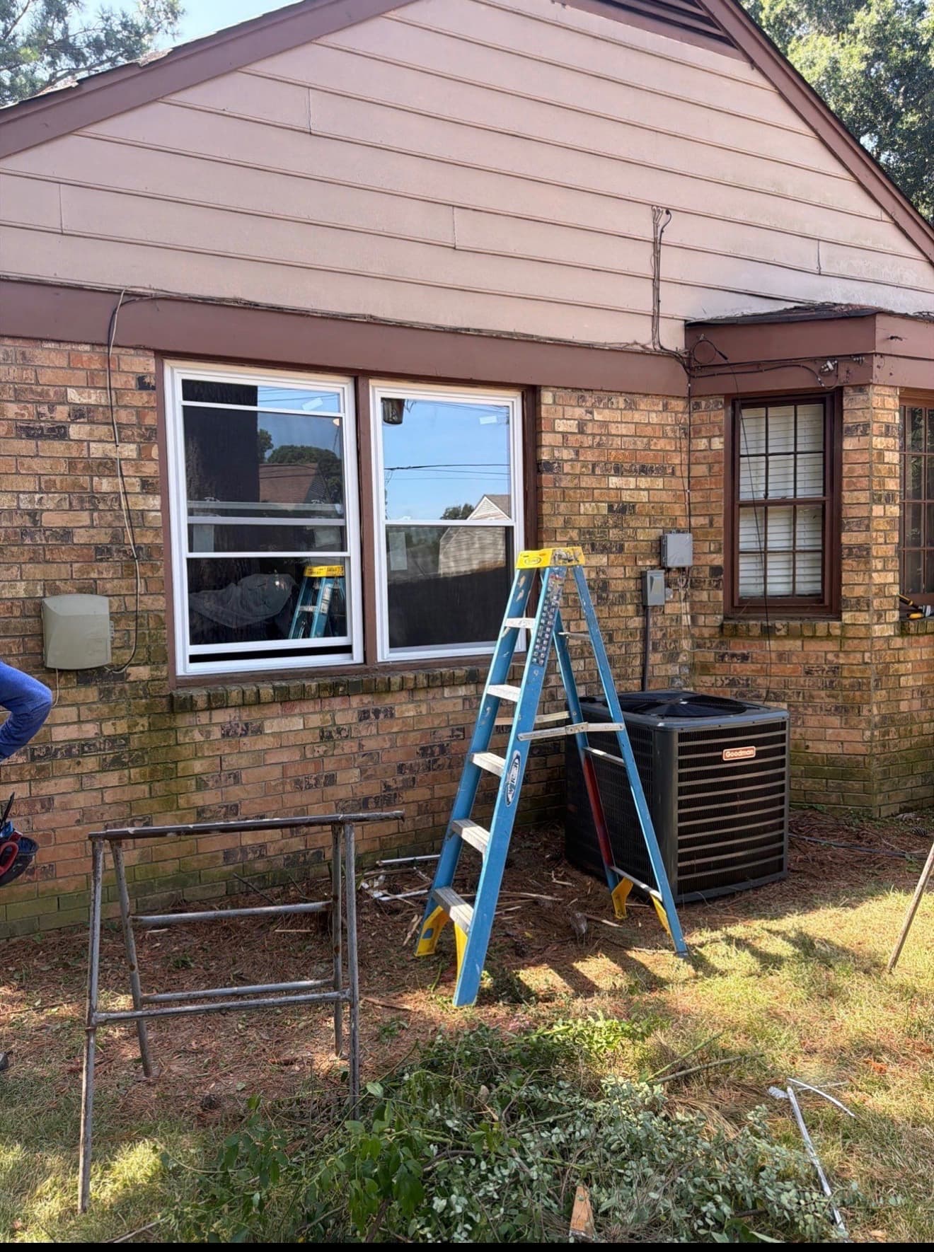 Newly installed white vinyl replacement windows in a brick home with a ladder still in place